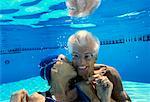 Mature Woman Kissing Mature Man Underwater in Swimming Pool