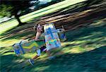 Boy Running through Field in Cardboard Airplane