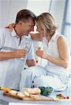 Couple Laughing in Kitchen Holding Glasses of Wine