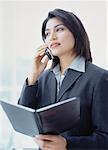 Businesswoman Using Cell Phone Holding Agenda