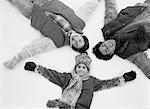 Overhead View of Family Lying in Snow Making Snow Angels