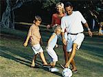 Family Playing with Soccer Ball In Park