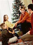 Famille réuni autour des arbres de Noël, échange de cadeaux