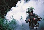 Soldier Wearing Camouflage Emerging from Smoke in Jungle