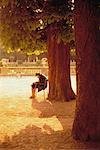 Mature Woman Sitting in Chair Under Tree, Paris, France