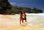 Couple en maillot de bain, en cours d'exécution dans le Surf sur la plage, République dominicaine, Caraïbes