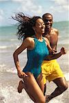 Couple in Swimwear Running in Water on Beach