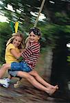 Portrait of Boy and Girl Sitting On Swing