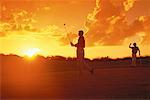 Hommes, jouer au golf au coucher du soleil