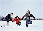 Famille marchant dans le champ de neige profonde, main dans la main