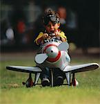 Portrait of Boy Wearing Goggles Sitting in Toy Airplane Outdoors