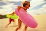 Children in Swimwear, Running on Beach with Inner Tubes Miami Beach, Florida, USA