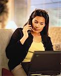 Woman Sitting on Sofa, Using Laptop and Telephone