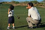 Back View of Father Teaching Son To Golf