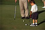 Back View of Boy Golfing with Father Watching