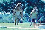 Father and Son Carrying Mother And Daughter on Backs Outdoors