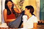 Zwei Frauen sitzen auf der Terrasse mit Schnurlostelefon, Lächeln