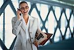 Businesswoman Using Cell Phone Holding Newspaper and Agenda