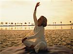 Mature femme pratiquant le Yoga sur la plage au coucher du soleil, la Floride, Etats-Unis