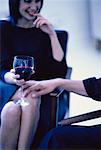 Woman Sitting in Chair with Glass Of Wine and Man's Hand on Knee