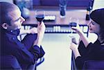 Man and Woman Sitting in Chairs Holding Glasses of Wine