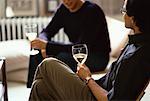 Male Couple Sitting in Chairs Holding Glasses of Wine