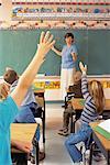 Students with Hands Raised in Classroom with Female Teacher