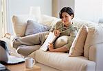 Portrait of Young Woman Relaxing On Sofa, Holding Newspaper