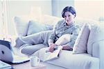 Portrait of Young Woman Relaxing On Sofa with Newspaper