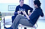 Male Couple Sitting in Chairs Toasting with Glasses of Wine