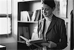 Female Teacher Reading Textbook In Classroom