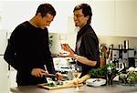 Male Couple Preparing Food in Kitchen with Glasses of Wine