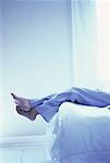 Man's Feet Hanging over Foot of Bed