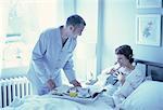 Man Bringing Breakfast to Woman In Bed with Book