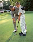 Grandfather Giving Grandson Golfing Lessons