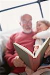 Grandfather Sitting on Sofa Reading to Grandchild