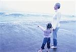 Grandmother and Granddaughter Standing in Surf on Beach