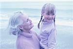 Große Großmutter und Enkelin stehen am Strand