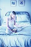 Femme assise sur le lit en lisant le journal, la détention de bol de céréales