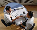 Overhead View of Businessmen at Desk, Shaking Hands