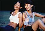 Deux femmes assises à l'extérieur de partage bouteille d'eau