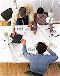 Overhead View of Business People In Meeting with Blueprints