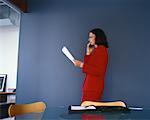 Geschäftsfrau, stehend, mit Handy, Dokument lesen
