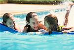 Trois filles sur le dispositif de flottaison en piscine