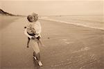 Grandmother Carrying Granddaughter in Surf on Beach