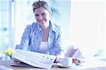 Portrait of Woman Sitting at Table, Holding Newspaper