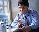 Homme d'affaires détenant journal lecture tasse de café dans le café