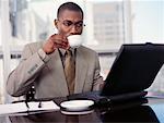 Businessman Sitting at Table with Laptop, Drinking from Mug