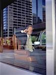 View of Businessman Using Cell Phone through Restaurant Window