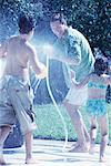 Family Having Water Fight in Driveway